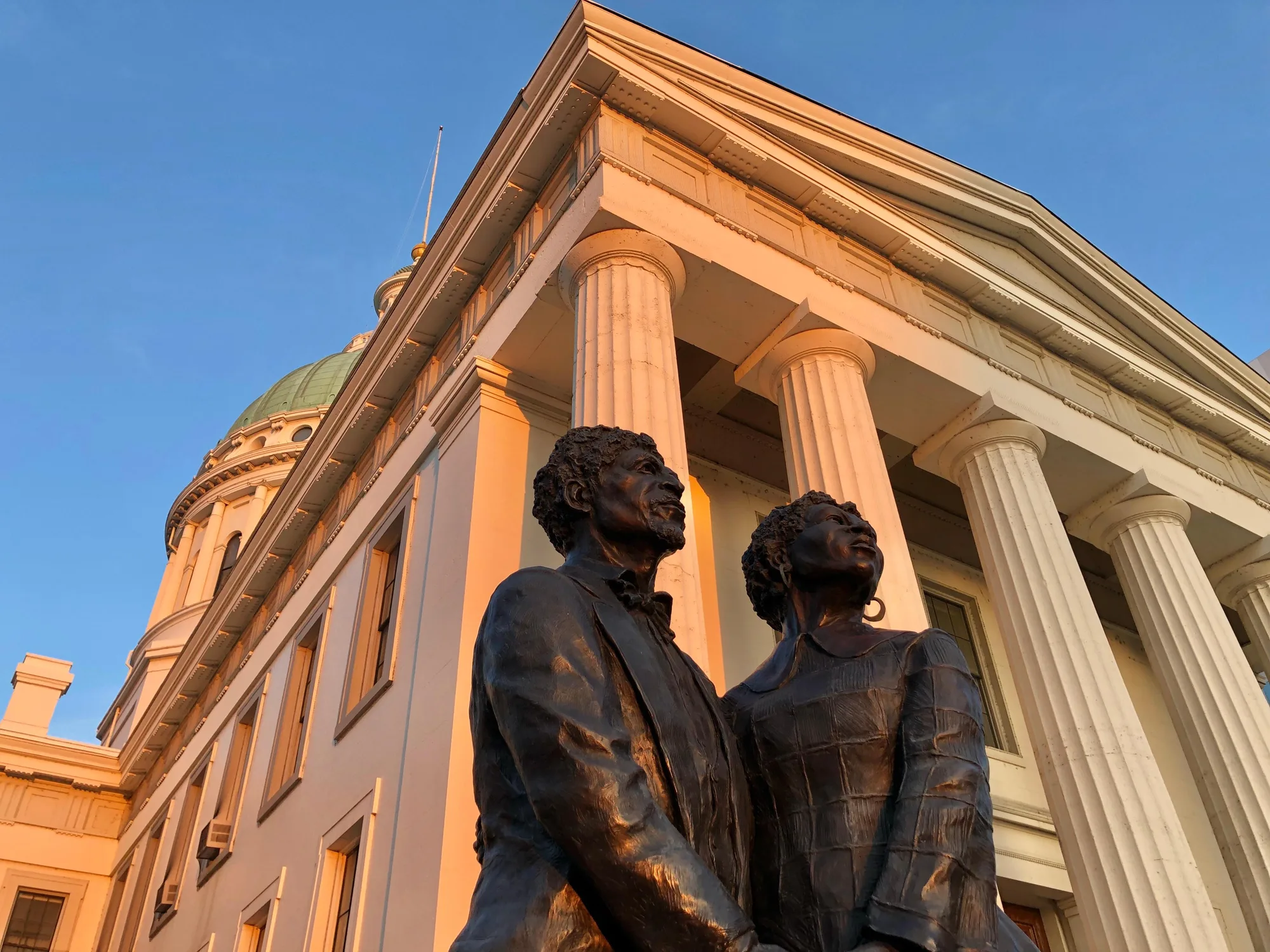 Statue of Dred and Harriet Scott looking toward the Gateway Arch, with the Old Courthouse dome behind them, St. Louis