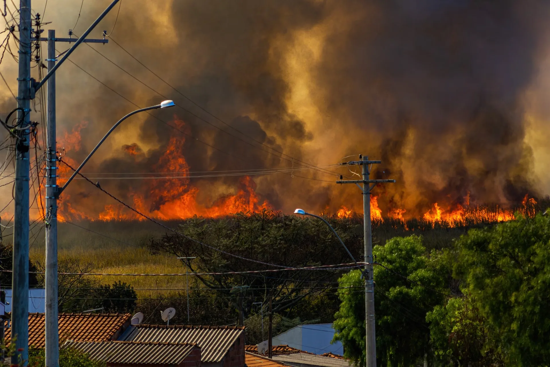 Wildfire burning through open land close to homes at a wildland-urban interface