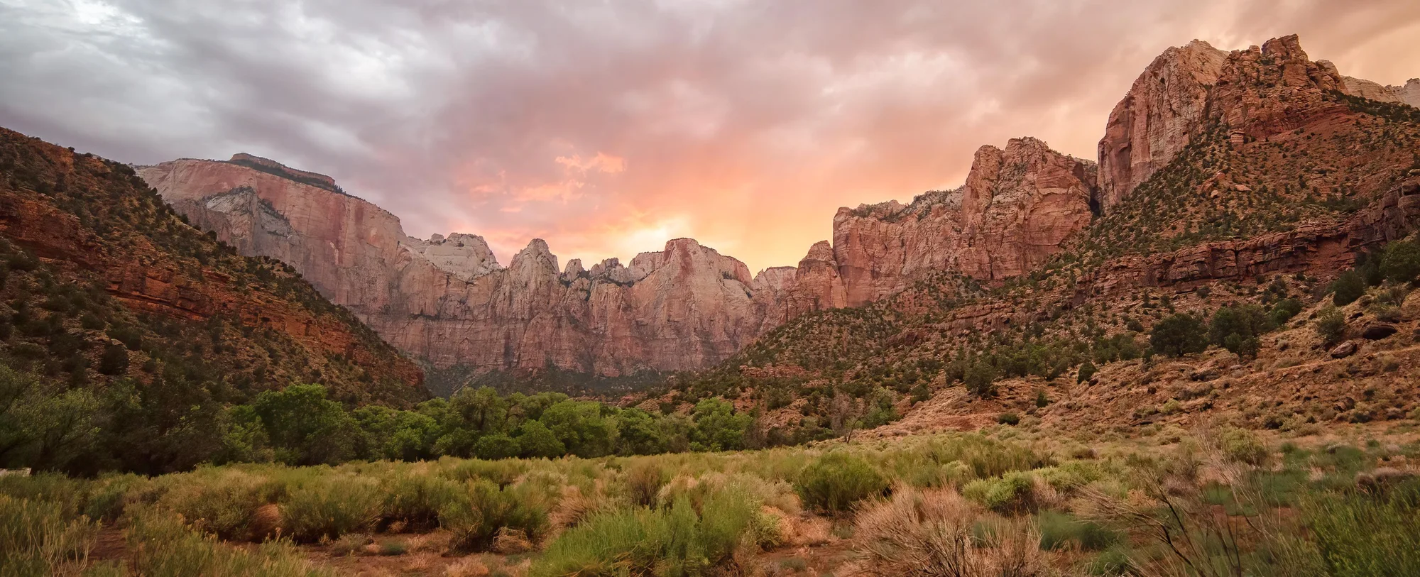 The sun sets behind red and white sandstone towers in Zion National Park